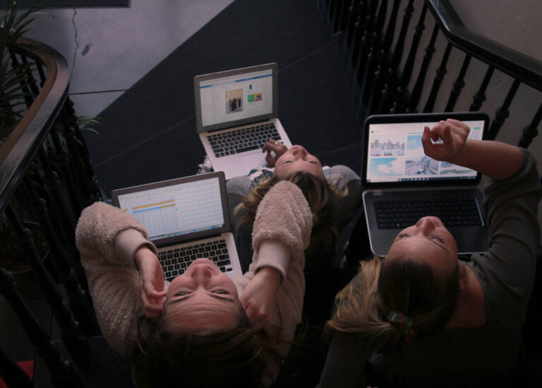 Symbolbild mit drei Mädchen mit einem Laptop, die nach oben schauen.
